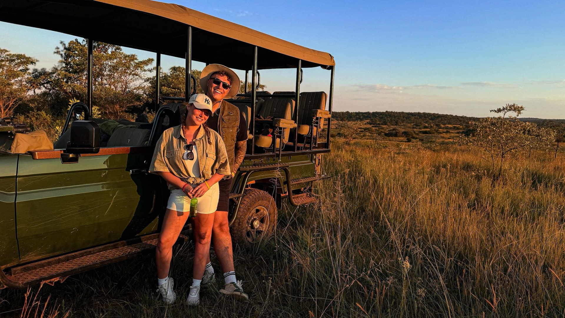 Victoria and Jamie beside a safari truck in the evening light